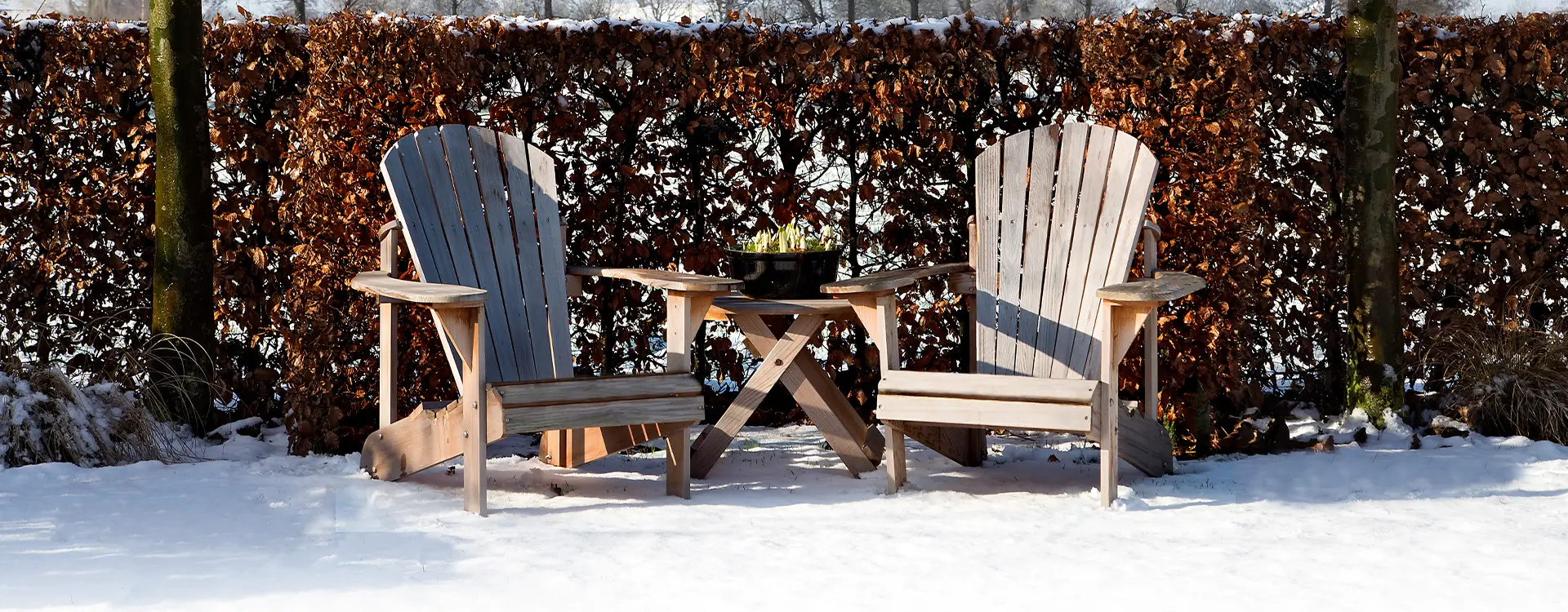 Twee houten adirondack stoelen in de sneeuw